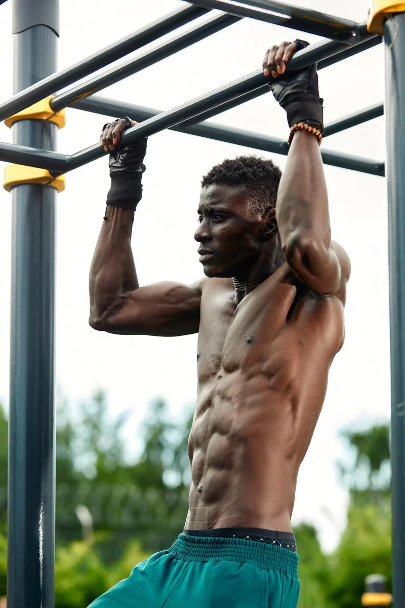 Athlete hanging from a pull-up bar at an outdoor exercise park