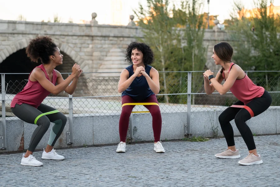 Three women training squats with exercise bands