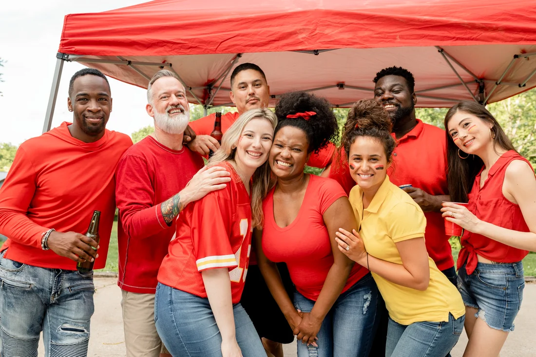 Diverse group of adults gathered beneath a canopy at a community event